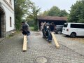 Personen stehen in 2 Reihen hintereinander und halten Holzbalken